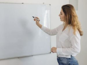 De jonge lerares schrijft op het schoolbord Wat is een zelfstandig naamwoord vertaalbureau Antwerpen