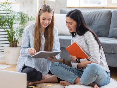 deux jeunes filles apprenant ensemble des langues etrangeres a la maison assises par terre Combien de langues dans le monde Agence de traduction Paris