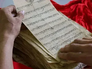 Mains feuilletant des manuscrits anciens ecrits en sanskrit langue la moins parlee au monde Agence de traduction Paris