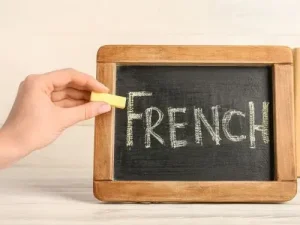 Main ecrivant le mot French a la craie sur un petit tableau noir le mot le plus long en français Agence de traduction Paris