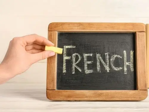 Main écrivant le mot French à la craie sur un petit tableau noir le mot le plus long en français Agence de traduction Paris Main ecrivant le mot French a la craie sur un petit tableau noir le mot le plus long en français Agence de traduction Paris