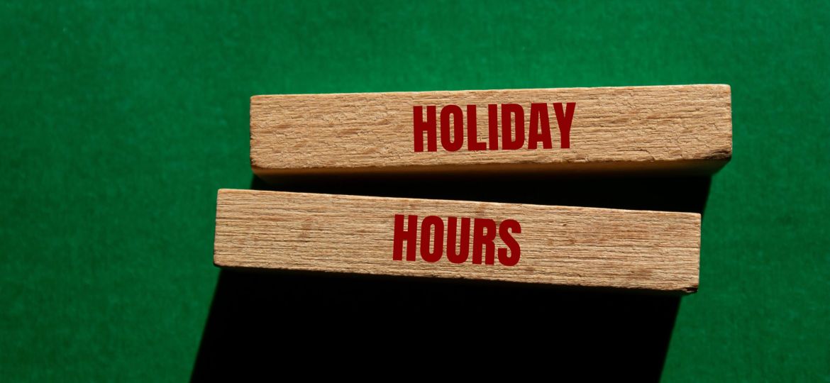 Holiday,Hours,Message,Written,On,Wooden,Blocks,On,Green,Background.