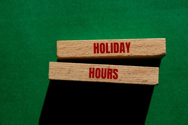 Holiday,Hours,Message,Written,On,Wooden,Blocks,On,Green,Background.